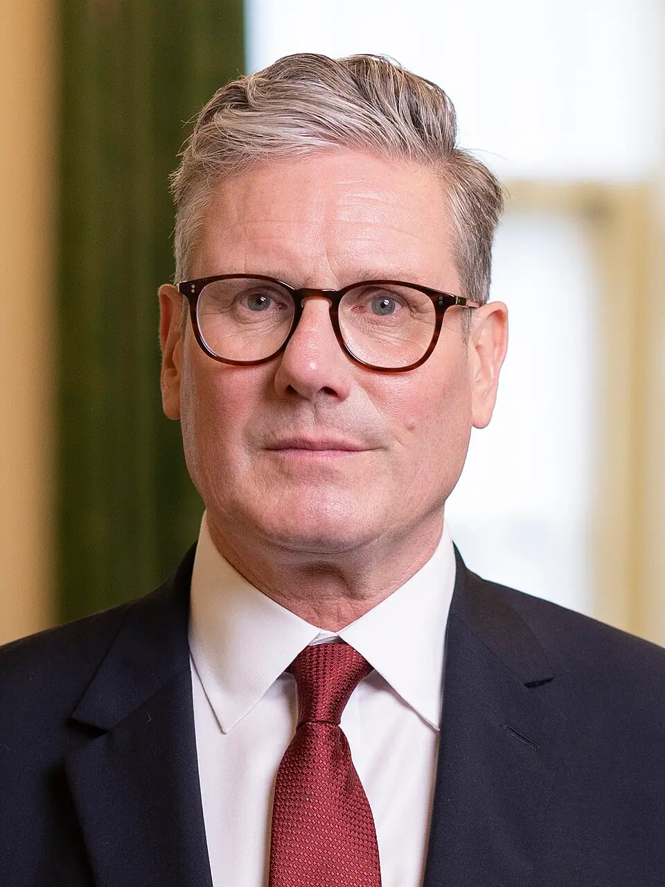 Official Downing Street portrait of Prime Minister Sir Keir Starmer (Wikimedia Commons)—identifies the party leader named in the copy; not the 18 May 2026 London small-business visit or the Leeds summit stage where rivals spoke the same weekend.
