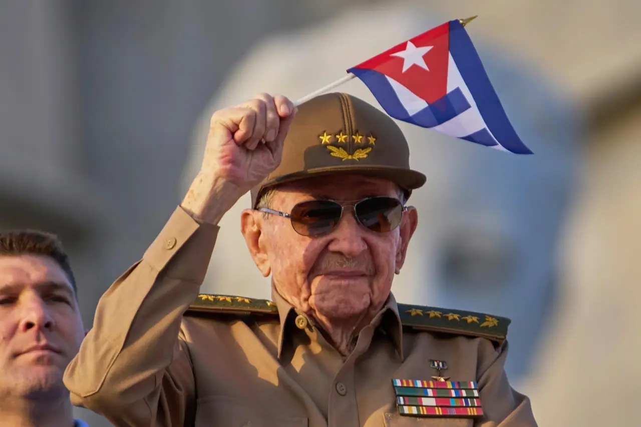 Raúl Castro in military uniform waving a Cuban flag (file photo from a previous public appearance; it does not depict the Miami press conference or indictment unsealing).